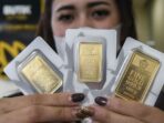 Wanita menunjukkan emas batangan Logam Mulia Emas Antam dari ukuran 25 gram hingga 100 gram di butik resmi